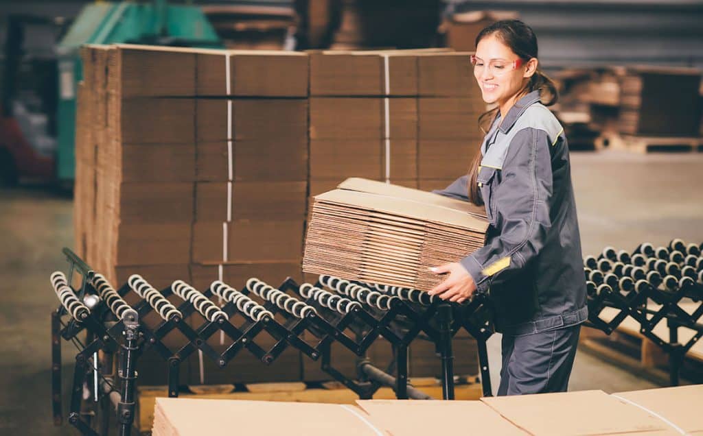 Production Facility Worker Lifts Corrugated Boxes for Placement on Pallet