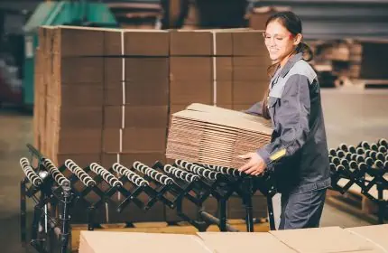 Production Facility Worker Lifts Corrugated Boxes for Placement on Pallet