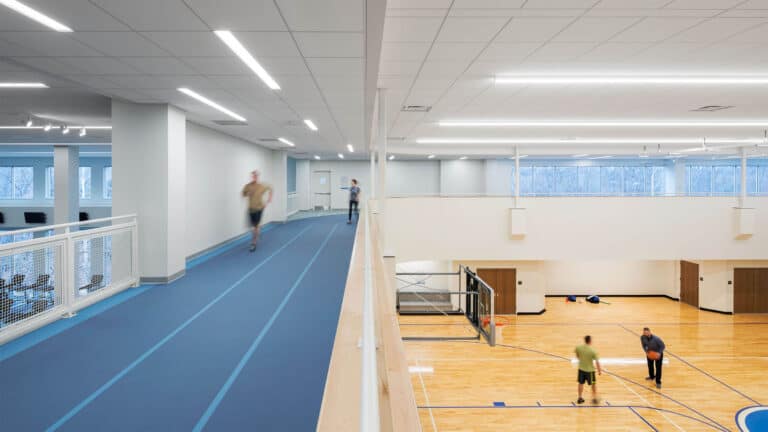 Indoor running track on mezzanine overlooking basketball courts and gym space at sports and athletic facility