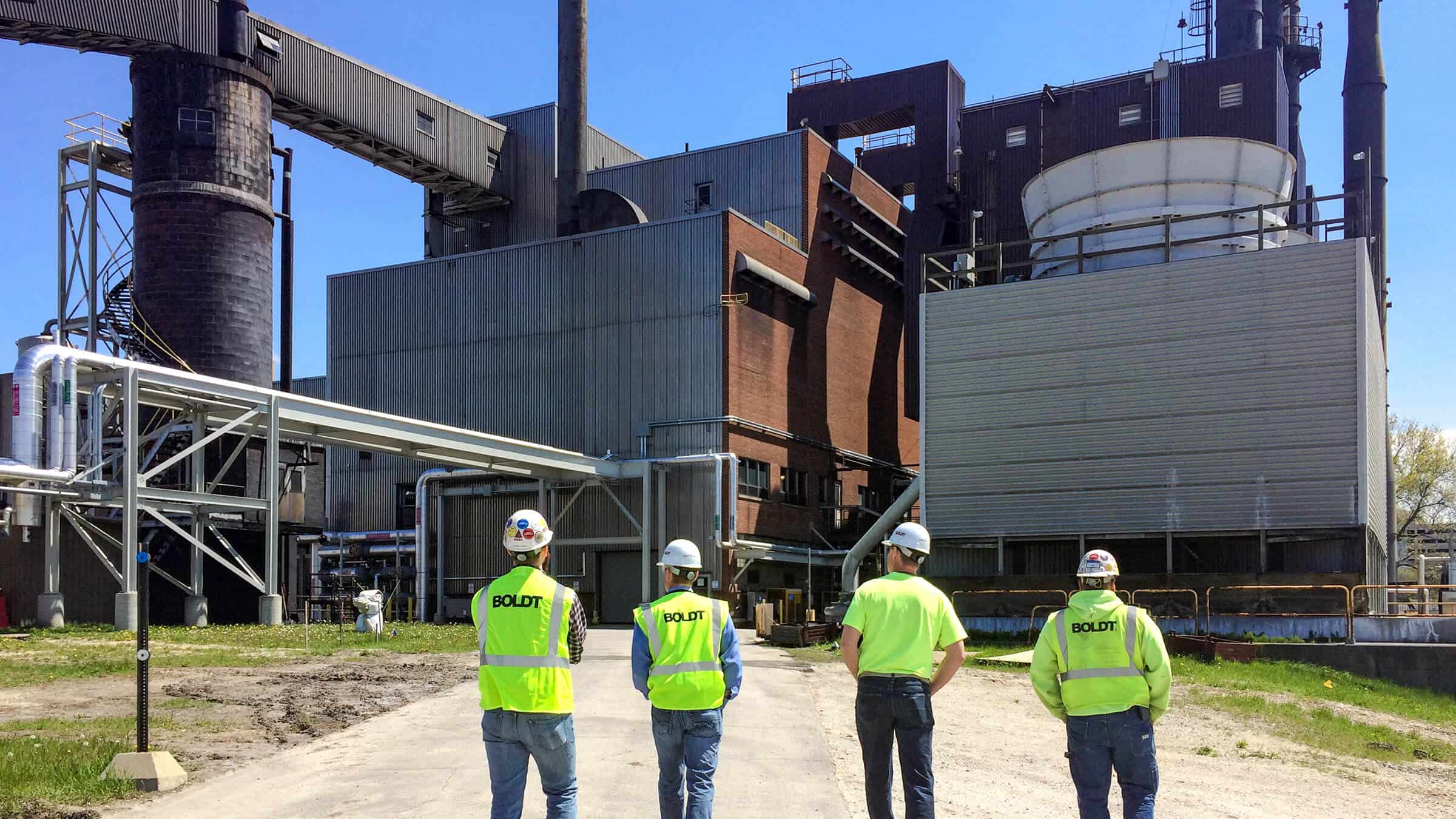 at central utility plant four boldt employees wearing neon vests facing towards central energy plant