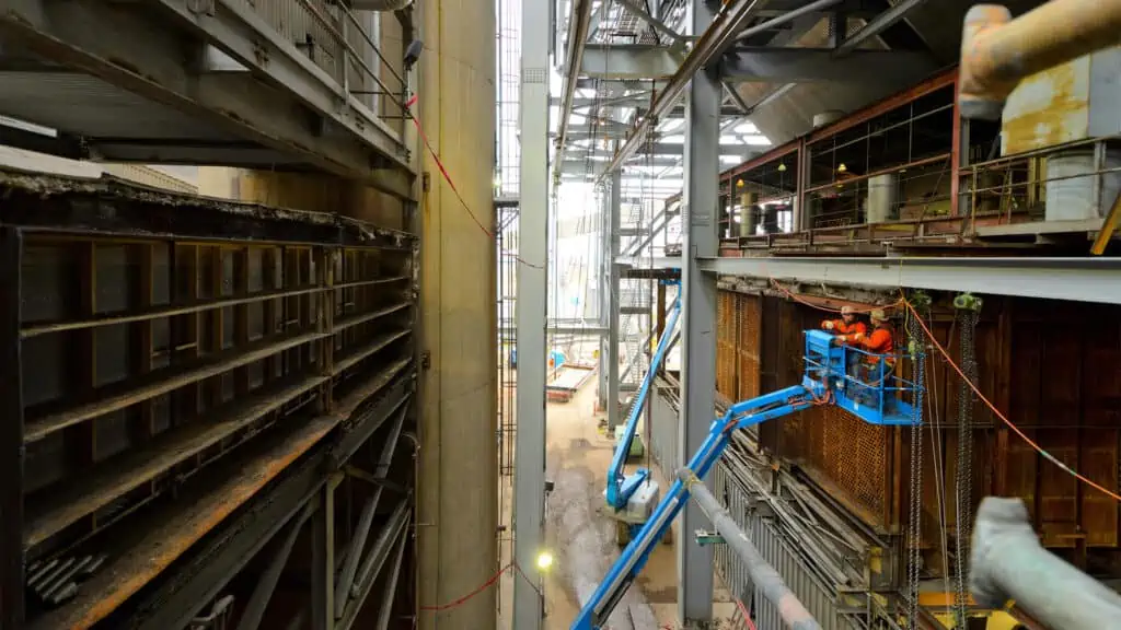 power plant construction - two workers in scissor lift working on building