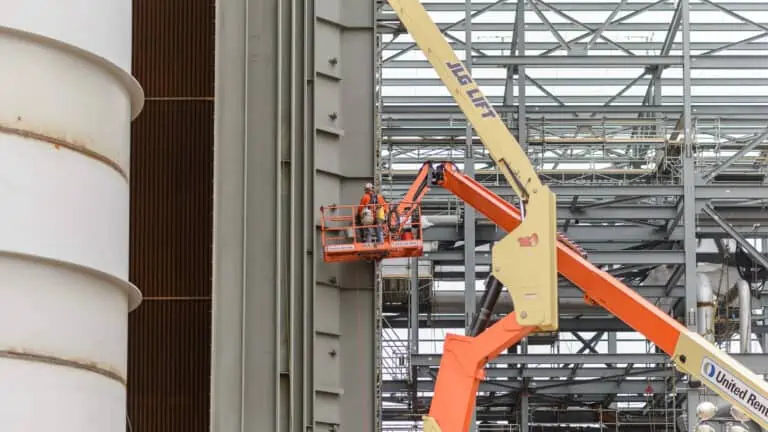 Worker on JLG scissors lift to work on exterior metal structure