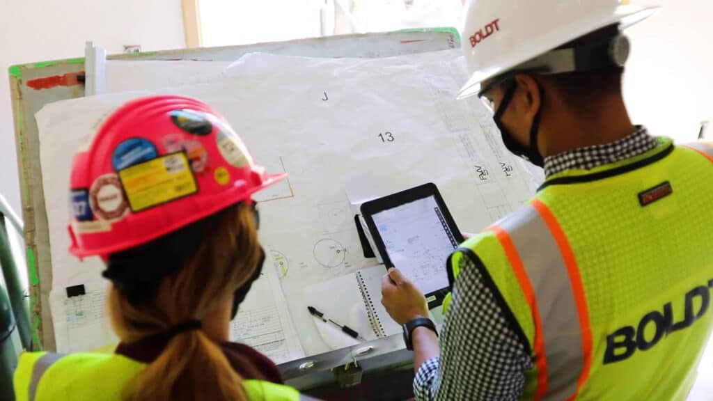 two Boldt team members looking at blueprints