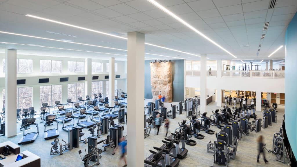 gym facility with rows of workout equipment and climbing wall
