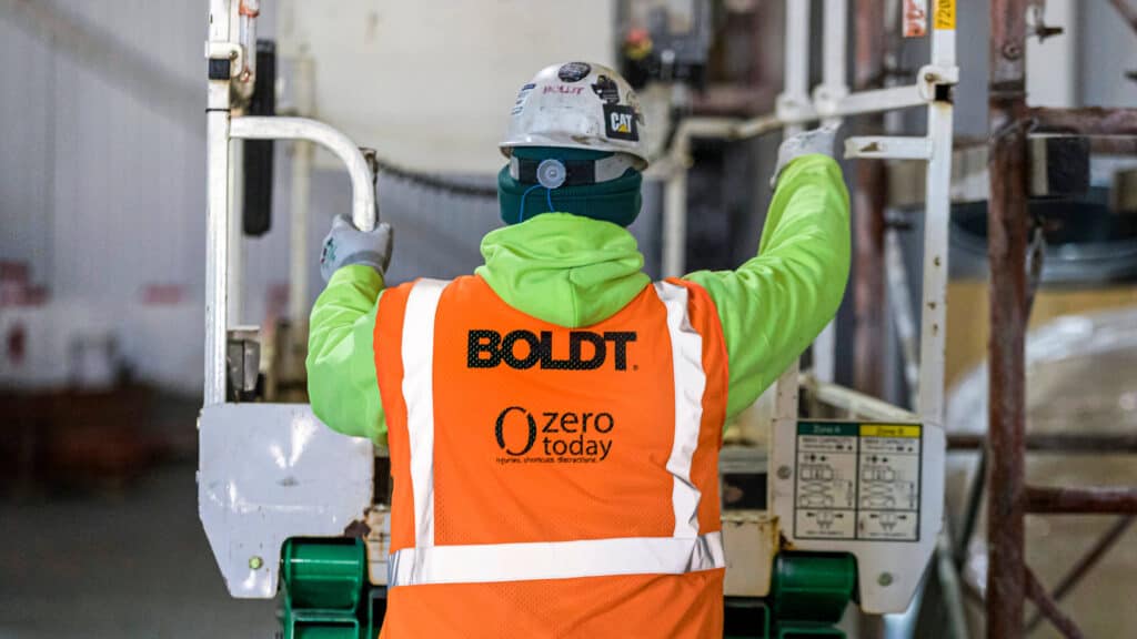 Boldt Construction Worker climbing onto lift equipment