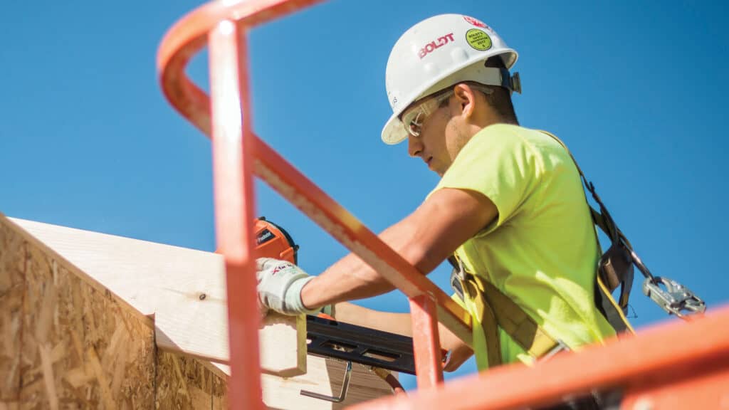 Construction worker on lift working on roof framing