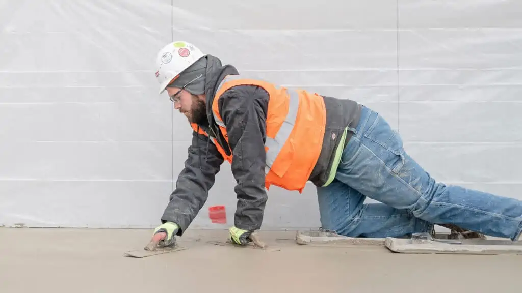 Construction worker on hands and knees laying concrete