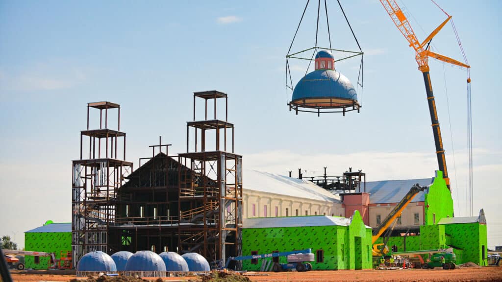 crane hoisting large dome onto a tower of a building