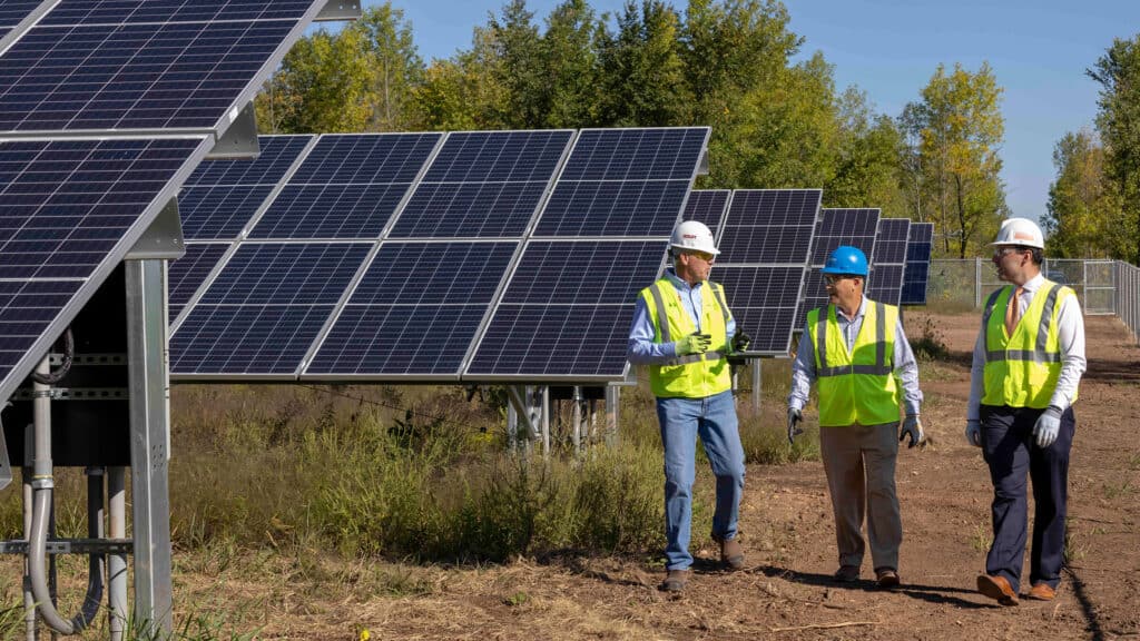 three boldt technicians standing besides a few rows of solar panels