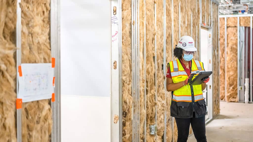female employee at job site inspecting details on ipad
