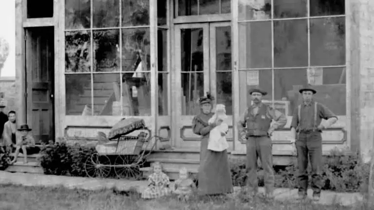 Black and white photo of family in front of home in 1889