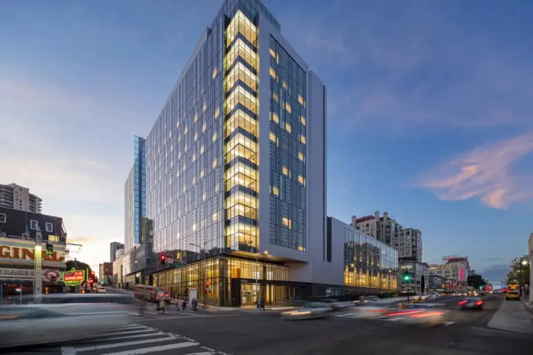 Sutter Health CPMC Van Ness Hospital building lit at dusk at busy street corner