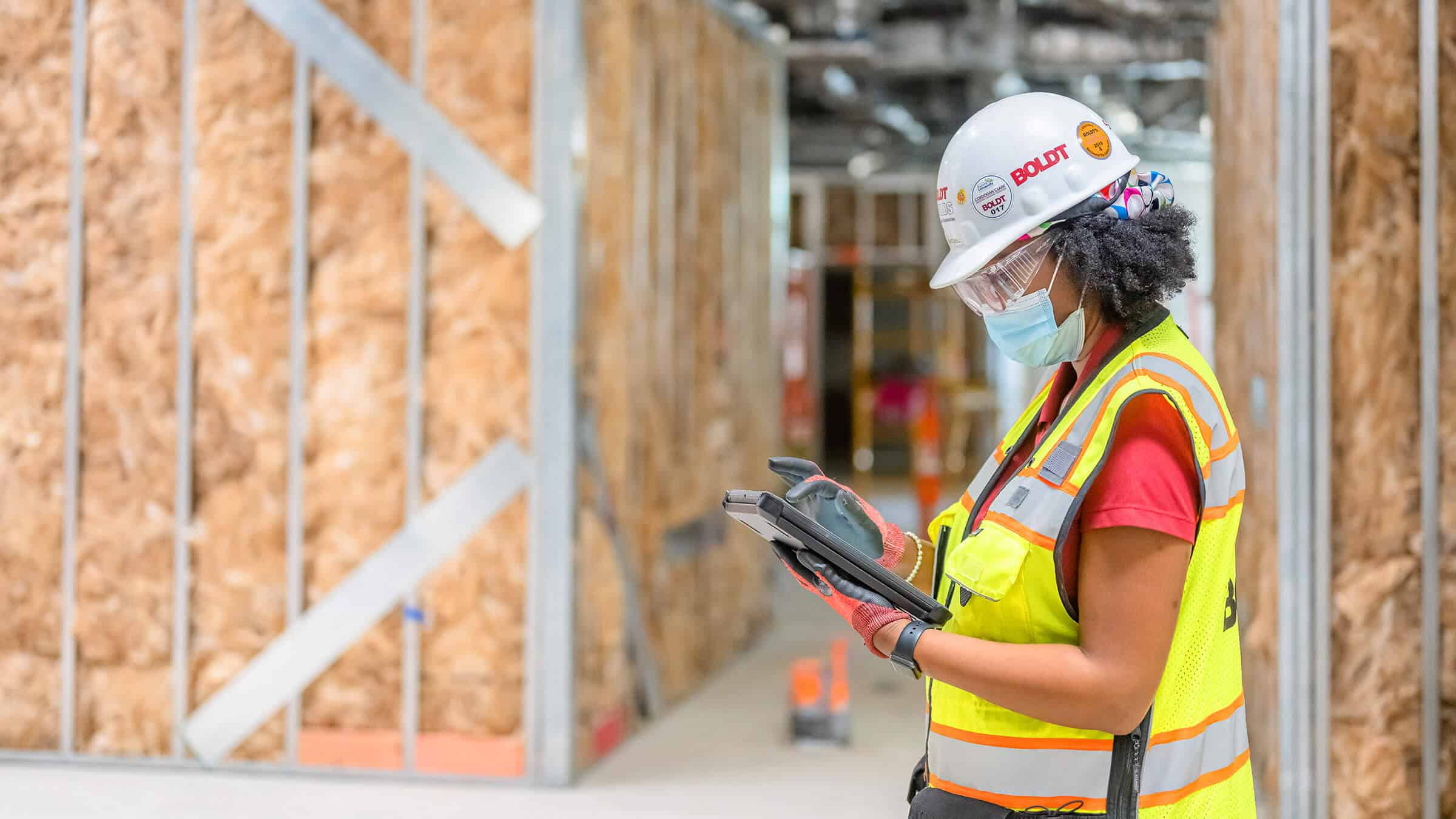 Construction worker stands among modular units while reading on a tablet