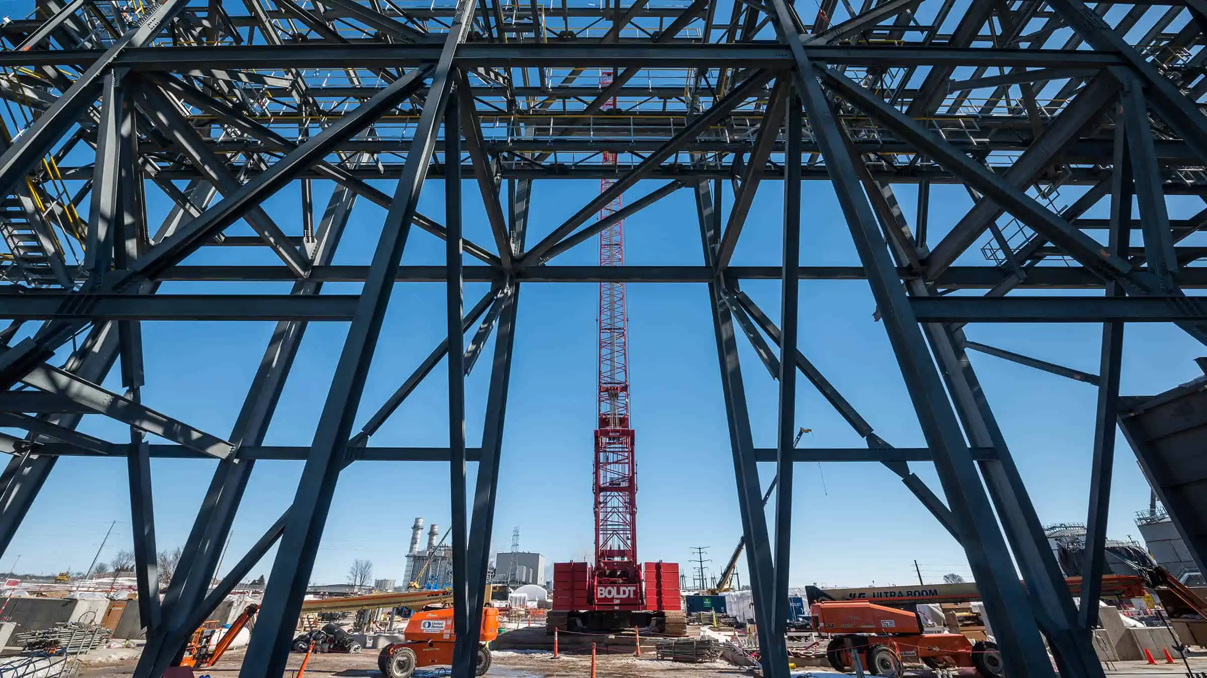 Structural steel framework in foreground with crane in background