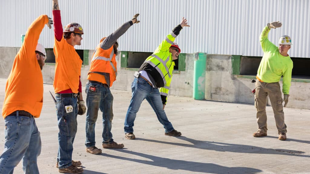group of construction workers doing stretches at work