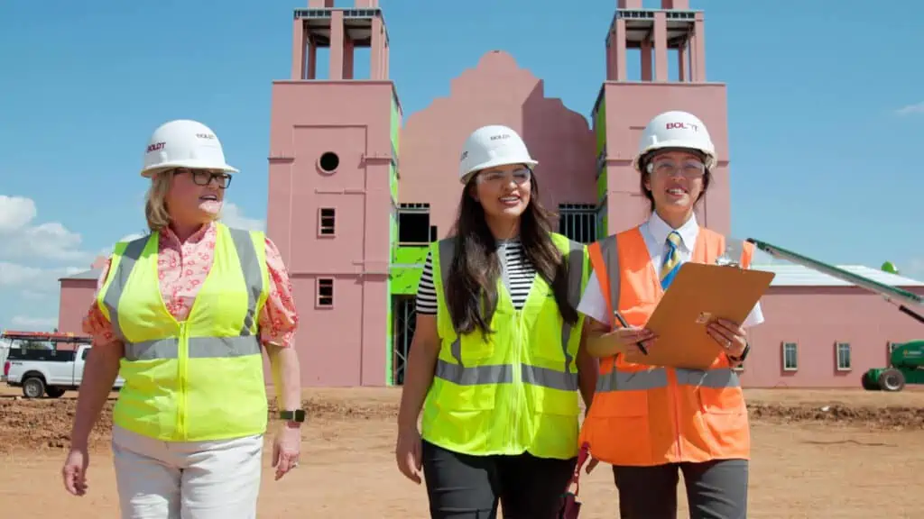 two young interns and a construction supervisor walking outside a religious construction site