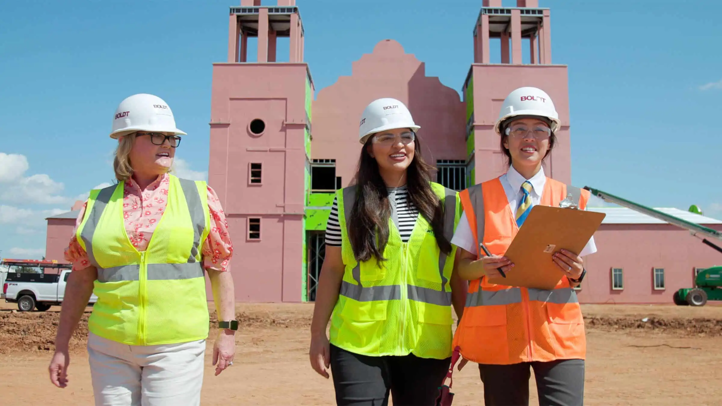 Two young interns and supervisor walking outside a religious construction site