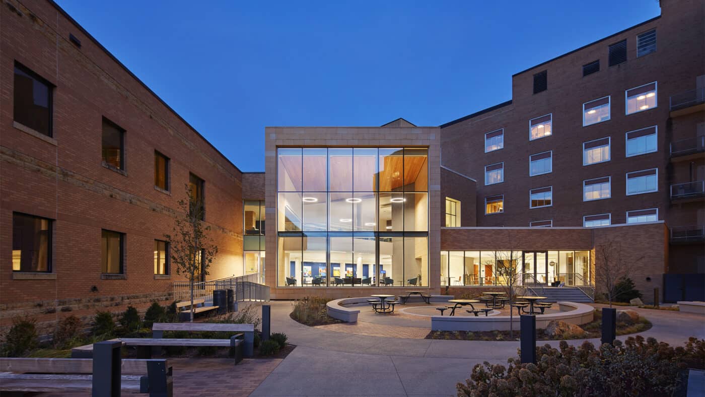 Mayo Clinic Health System - Mankato Hospital Exterior Patio Area with View of Patient Hub Interior Lit at Night