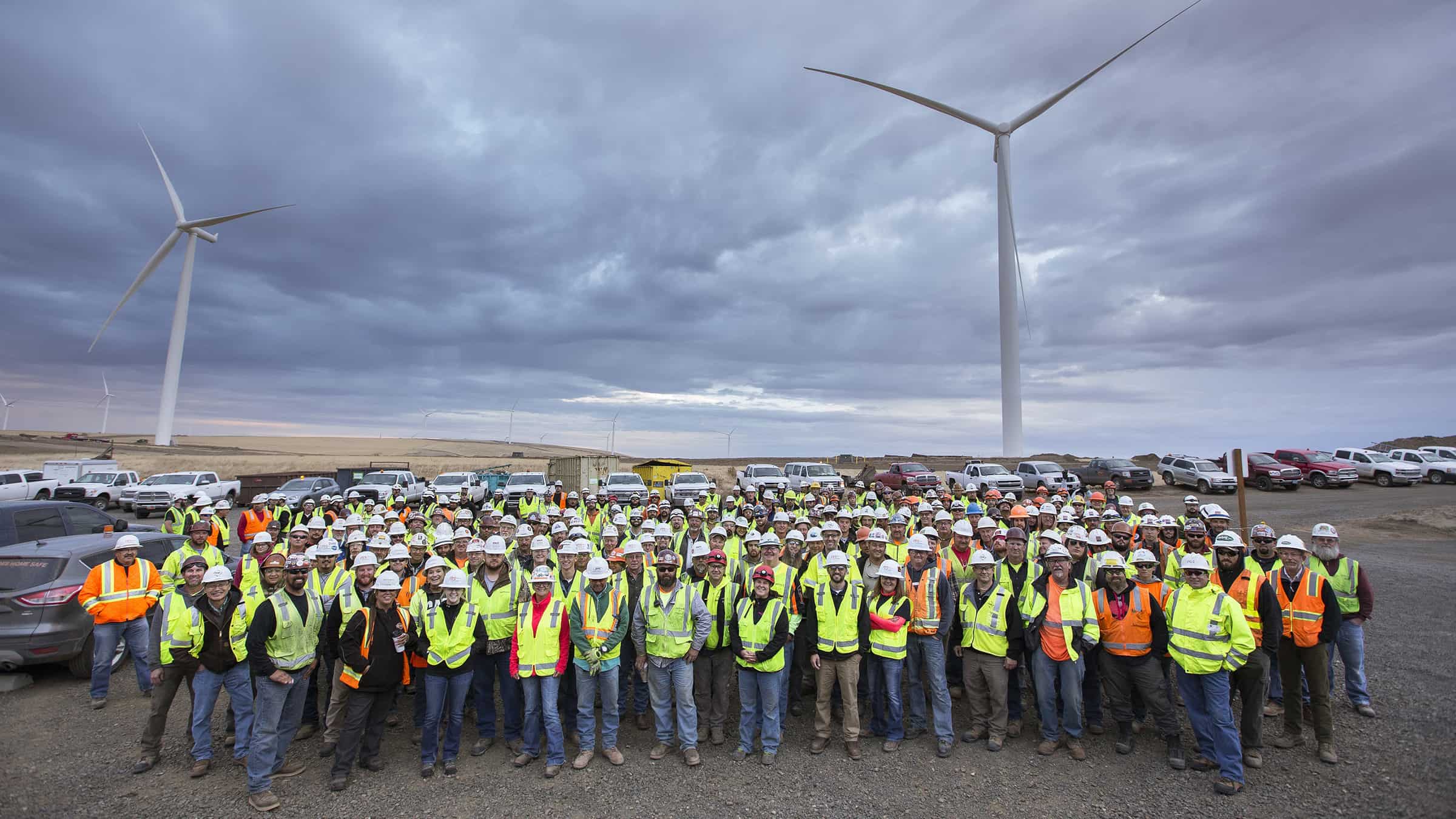 Portland General Electric Company - Tucannon River Wind Farm - Group of Employees Standing in Parking Lot Beneath Two Wind Turbines