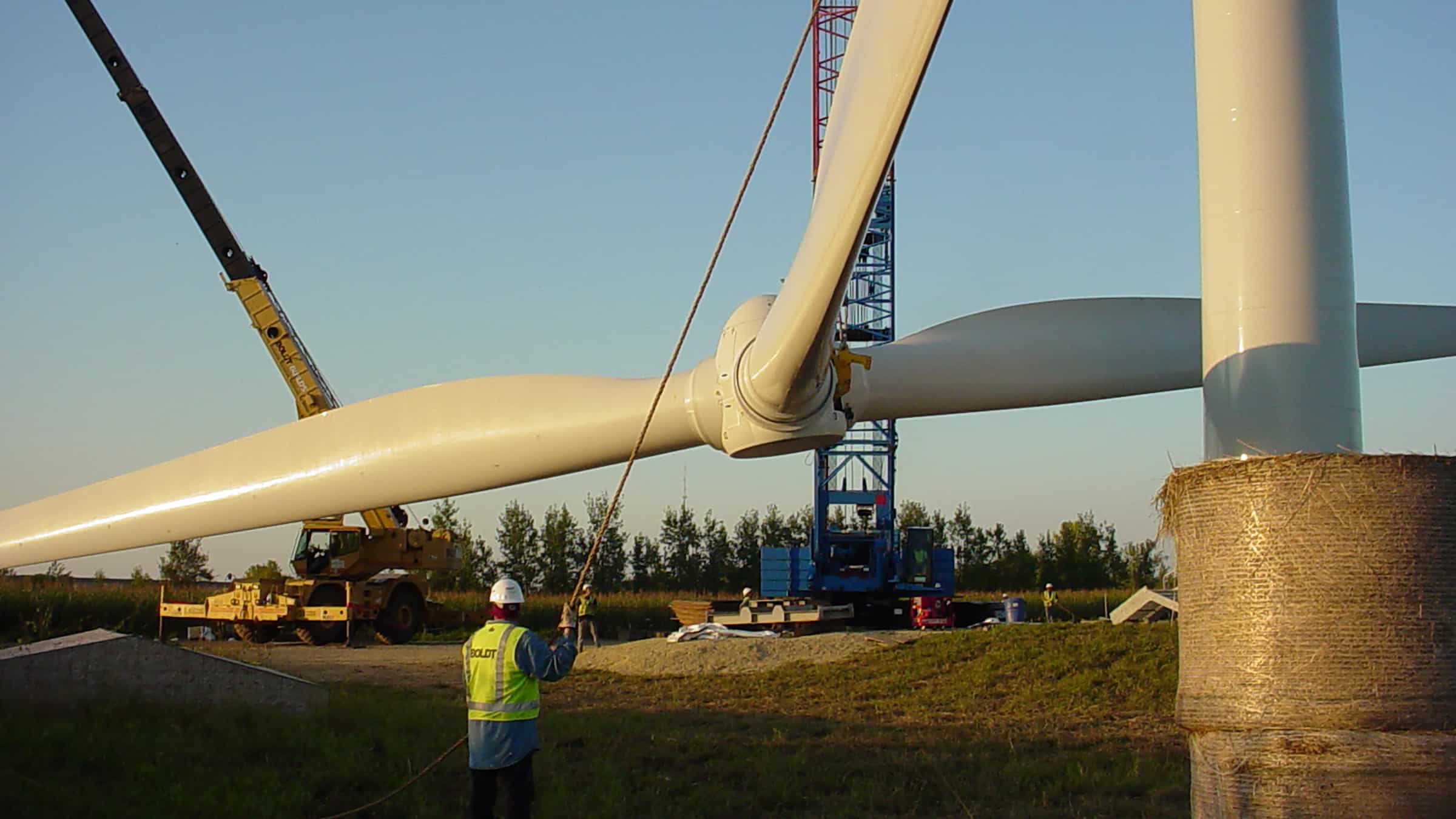 St. Olaf College - Wind Turbine Erection of Blades by Two Boldt Cranes. Boldt Employee in Foreground Guiding Lift