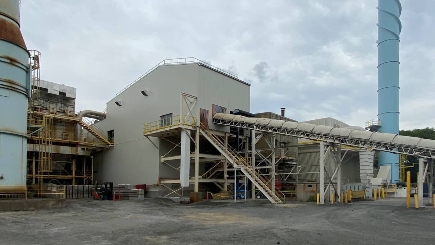 USG Interiors - Manufacturing Facility Exterior View of Conveyor System, Building, Stack