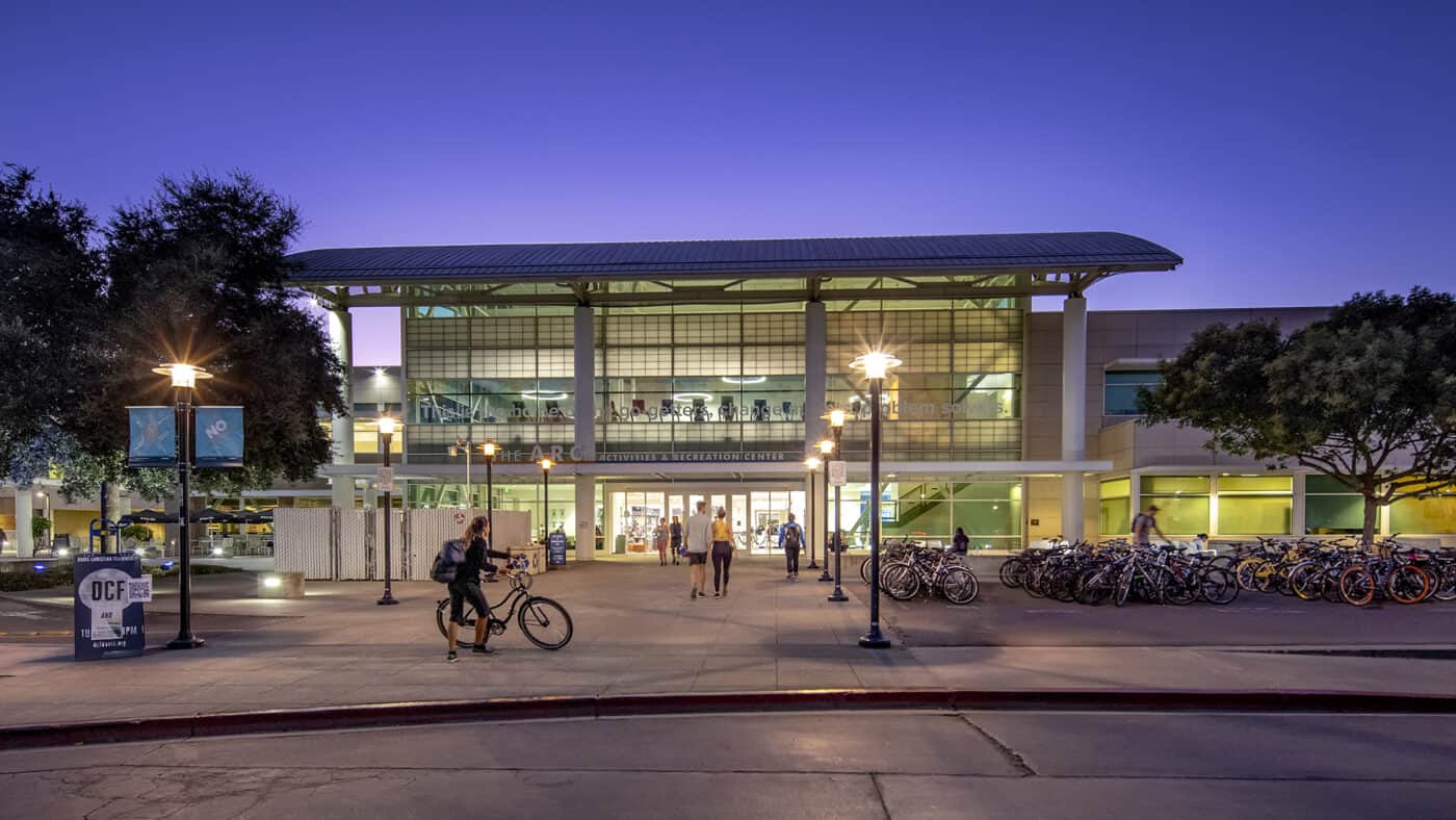 University of California - Davis - Activities and Recreation Center Building Exterior Lit at Dusk with Bicycle Racks in Foreground