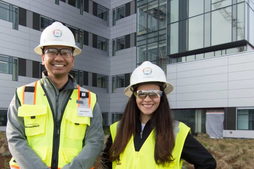 two smiling workers in front of a building