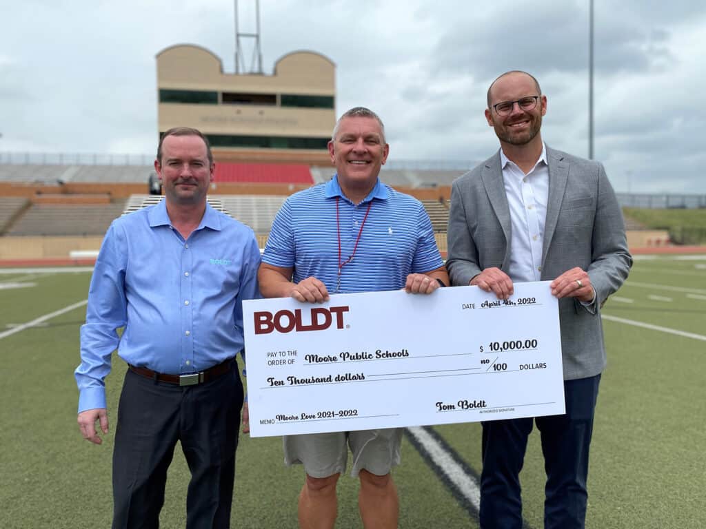 Boldt Oklahoma City employees hold oversized check to Moore Public Schools