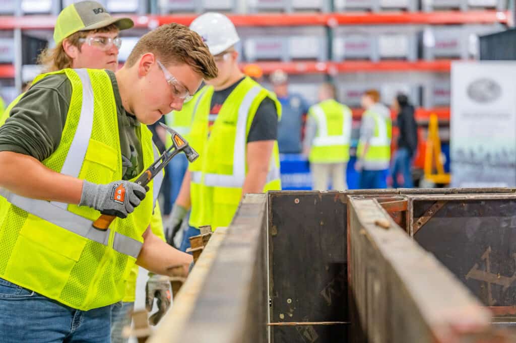 Students in safety gear working with hammer and other construction equipment